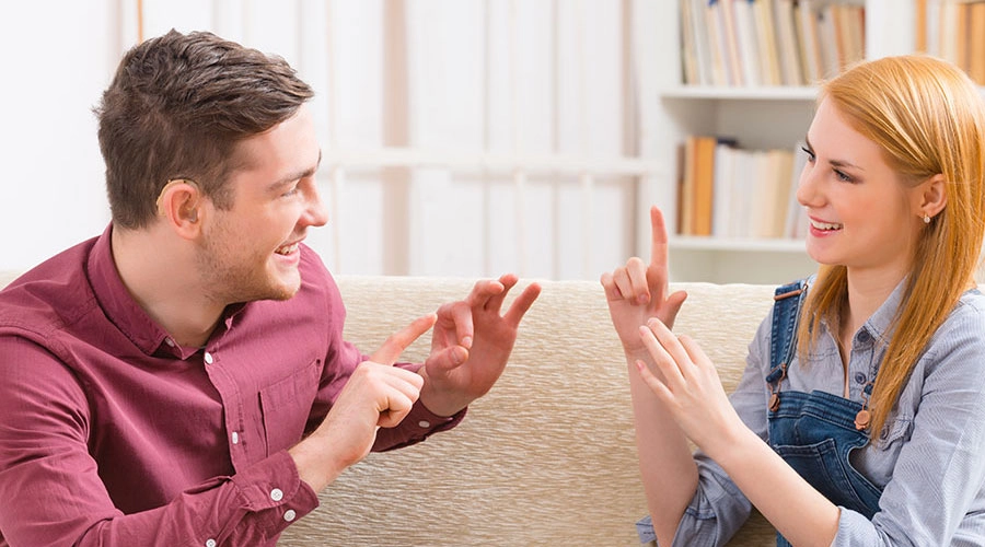 child learning sign language with hearing aid سمعک و زبان اشاره: مکمل یا جایگزین؟ راهنمای انتخاب بهترین روش ارتباطی کارمند با سمعک و استفاده از زبان اشاره در جلسه