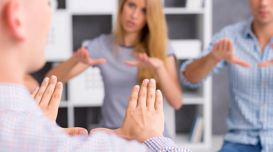 hearing aid user practicing sign language سمعک و زبان اشاره: مکمل یا جایگزین؟ راهنمای انتخاب بهترین روش ارتباطی مربی در حال تمرین زبان اشاره با بزرگسالان
